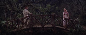 Movie still from “The Music Man” (1962), directed by Morton DaCosta – A man in a tan suit crossing a bridge; Wide shot, High angle