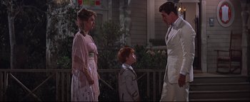 Movie still from “The Music Man” (1962), directed by Morton DaCosta – A man and a woman standing next to a young boy; Medium shot, Over the shoulder angle