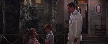 Movie still from “The Music Man” (1962), directed by Morton DaCosta – A man and a woman standing next to a young boy and a little boy; Medium shot, Over the shoulder angle