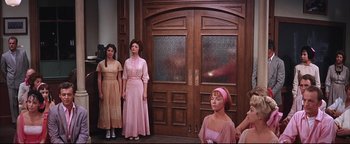 Movie still from “The Music Man” (1962), directed by Morton DaCosta – A group of women standing in front of a wooden door; Wide shot, Low angle