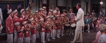 Movie still from “The Music Man” (1962), directed by Morton DaCosta – A group of people in red and white uniforms playing musical instruments; Wide shot, High angle