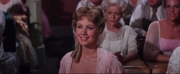 Movie still from “The Music Man” (1962), directed by Morton DaCosta – A woman in a pink dress and a woman in a white dress and a man in a white dress; Close Up shot, Over the shoulder angle