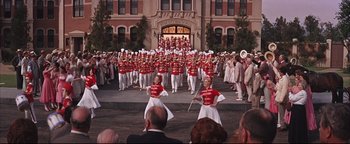 Movie still from “The Music Man” (1962), directed by Morton DaCosta – A group of men and women in red and white uniforms; Extreme Wide shot, High angle