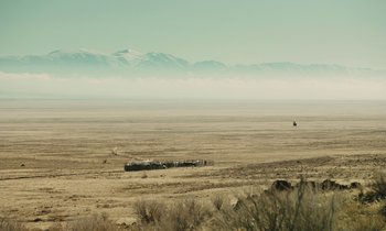 Movie still from “The Mustang” (2019), directed by Laure de Clermont-Tonnerre – A train traveling through a desert with mountains in the background; Extreme Wide shot, Low angle