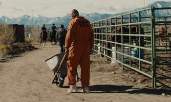 Movie still from “The Mustang” (2019), directed by Laure de Clermont-Tonnerre – A man in an orange suit walking down a dirt road; Wide shot, Over the shoulder angle