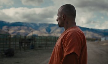 Movie still from “The Mustang” (2019), directed by Laure de Clermont-Tonnerre – A man in an orange shirt is looking at the mountains; Close Up shot, Over the shoulder angle