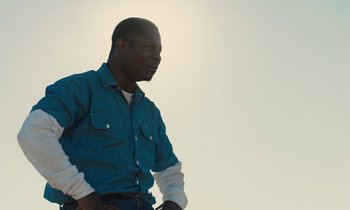Movie still from “The Mustang” (2019), directed by Laure de Clermont-Tonnerre – A man in a blue shirt is standing outside; Medium shot, Low angle