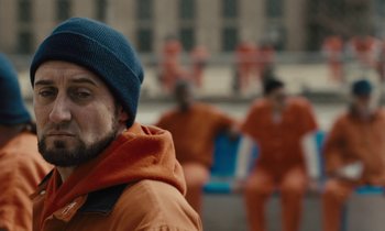 Movie still from “The Mustang” (2019), directed by Laure de Clermont-Tonnerre – A man in an orange jacket and blue hat; Close Up shot, Over the shoulder angle