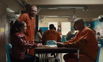 Movie still from “The Mustang” (2019), directed by Laure de Clermont-Tonnerre – A group of people sitting around a table; Wide shot, Over the shoulder angle