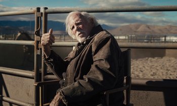 Movie still from “The Mustang” (2019), directed by Laure de Clermont-Tonnerre – An older man sitting in a chair with a fence in the background; Medium shot, Over the shoulder angle