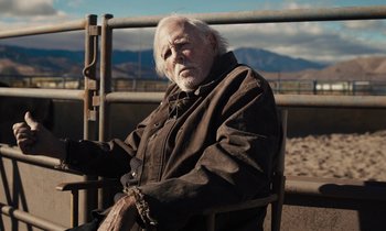 Movie still from “The Mustang” (2019), directed by Laure de Clermont-Tonnerre – An older man sitting in a chair with a chain around his neck; Medium shot, Over the shoulder angle
