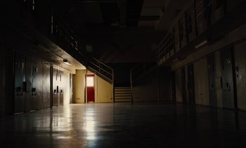 Movie still from “The Mustang” (2019), directed by Laure de Clermont-Tonnerre – An empty room with a red door and stairs; Extreme Wide shot, High angle