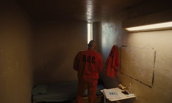 Movie still from “The Mustang” (2019), directed by Laure de Clermont-Tonnerre – A man standing in a room next to a window; Wide shot, High angle