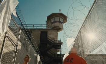 Movie still from “The Mustang” (2019), directed by Laure de Clermont-Tonnerre – Two men in orange shirts standing in front of a prison; Extreme Wide shot, Low angle
