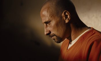 Movie still from “The Mustang” (2019), directed by Laure de Clermont-Tonnerre – A man with a bald head wearing an orange shirt; Close Up shot, High angle