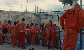 Movie still from “The Mustang” (2019), directed by Laure de Clermont-Tonnerre – A group of men in orange jumpsuits standing next to each other; Extreme Wide shot, High angle