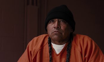 Movie still from “The Mustang” (2019), directed by Laure de Clermont-Tonnerre – A man in an orange shirt wearing a black hat; Close Up shot, Over the shoulder angle