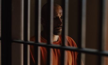Movie still from “The Mustang” (2019), directed by Laure de Clermont-Tonnerre – A man in an orange shirt behind bars; Close Up shot, Low angle