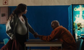 Movie still from “The Mustang” (2019), directed by Laure de Clermont-Tonnerre – A man and a pregnant woman shaking hands over a table; Medium shot, High angle