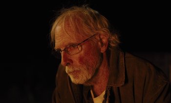 Movie still from “The Mustang” (2019), directed by Laure de Clermont-Tonnerre – An older man with a beard and glasses; Close Up shot, Over the shoulder angle