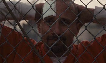 Movie still from “The Mustang” (2019), directed by Laure de Clermont-Tonnerre – A man with bandages on his head is sitting behind a fence; Close Up shot, High angle