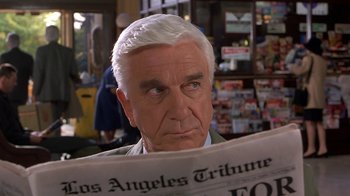 Movie still from “Naked Gun 33 1/3: The Final Insult” (1994), directed by Peter Segal – An older man reading a newspaper in a store; Close Up shot, Low angle