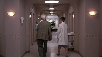 Movie still from “Naked Gun 33 1/3: The Final Insult” (1994), directed by Peter Segal – A man and a woman are walking down a hallway; Wide shot, Low angle