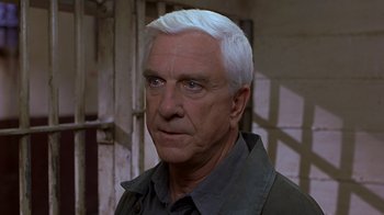 Movie still from “Naked Gun 33 1/3: The Final Insult” (1994), directed by Peter Segal – An older man with white hair looking at the camera; Close Up shot, Low angle