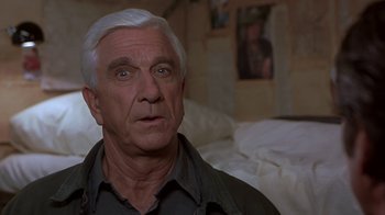 Movie still from “Naked Gun 33 1/3: The Final Insult” (1994), directed by Peter Segal – An older man with white hair looking at the camera; Close Up shot, Low angle