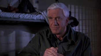 Movie still from “Naked Gun 33 1/3: The Final Insult” (1994), directed by Peter Segal – An older man sitting in front of a wall; Close Up shot, Over the shoulder angle