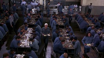 Movie still from “Naked Gun 33 1/3: The Final Insult” (1994), directed by Peter Segal – A group of people sitting at a table with plates of food in front of them; Wide shot, High angle