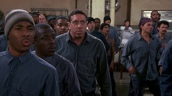 Movie still from “Naked Gun 33 1/3: The Final Insult” (1994), directed by Peter Segal – A group of men standing next to each other in a room; Medium shot, High angle