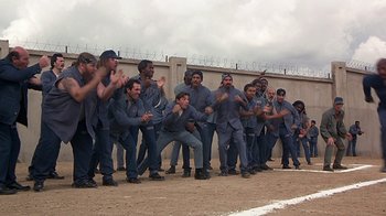 Movie still from “Naked Gun 33 1/3: The Final Insult” (1994), directed by Peter Segal – A group of men standing next to each other on top of a dirt field; Wide shot, High angle