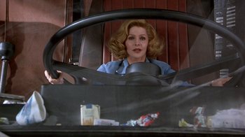Movie still from “Naked Gun 33 1/3: The Final Insult” (1994), directed by Peter Segal – A woman sitting in the driver's seat of a car; Medium shot, Low angle