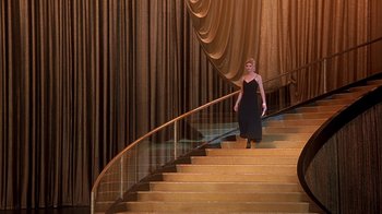 Movie still from “Naked Gun 33 1/3: The Final Insult” (1994), directed by Peter Segal – A woman in a black dress walking down a set of stairs; Wide shot, Low angle
