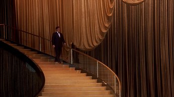 Movie still from “Naked Gun 33 1/3: The Final Insult” (1994), directed by Peter Segal – A man in a tuxedo walking down a set of stairs; Extreme Wide shot, Low angle