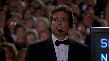 Movie still from “Naked Gun 33 1/3: The Final Insult” (1994), directed by Peter Segal – A man in a tuxedo is wearing a headset; Close Up shot, Low angle