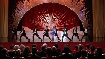 Movie still from “Naked Gun 33 1/3: The Final Insult” (1994), directed by Peter Segal – A group of people on a stage performing a dance; Wide shot, High angle