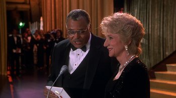 Movie still from “Naked Gun 33 1/3: The Final Insult” (1994), directed by Peter Segal – A man and a woman are standing next to each other; Medium shot, Over the shoulder angle