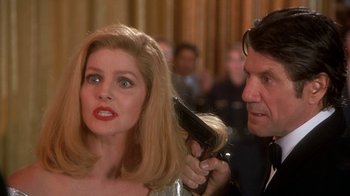 Movie still from “Naked Gun 33 1/3: The Final Insult” (1994), directed by Peter Segal – A woman with long blonde hair getting her hair blow dried by a man; Close Up shot, Over the shoulder angle