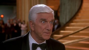 Movie still from “Naked Gun 33 1/3: The Final Insult” (1994), directed by Peter Segal – An older man in a tuxedo looking surprised; Close Up shot, High angle