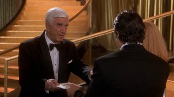 Movie still from “Naked Gun 33 1/3: The Final Insult” (1994), directed by Peter Segal – A man in a tuxedo and a man in a black tie; Medium shot, Over the shoulder angle