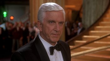 Movie still from “Naked Gun 33 1/3: The Final Insult” (1994), directed by Peter Segal – An older man wearing a tuxedo and a bow tie; Close Up shot, Over the shoulder angle