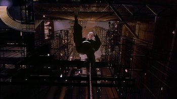 Movie still from “Naked Gun 33 1/3: The Final Insult” (1994), directed by Peter Segal – A man hanging from a rope in a building; Wide shot, Overhead angle