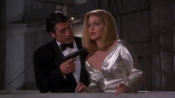 Movie still from “Naked Gun 33 1/3: The Final Insult” (1994), directed by Peter Segal – A man in a suit and a woman in a silver dress; Medium shot, Low angle