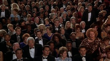 Movie still from “Naked Gun 33 1/3: The Final Insult” (1994), directed by Peter Segal – A large group of people in formal wear sitting in rows; Wide shot, High angle