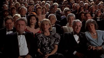 Movie still from “Naked Gun 33 1/3: The Final Insult” (1994), directed by Peter Segal – A group of people in formal wear sitting in a crowd; Wide shot, High angle