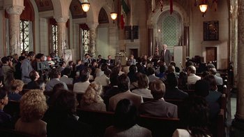 Movie still from “The Naked Gun: From the Files of Police Squad!” (1988), directed by David Zucker – A man is giving a speech in front of an audience; Extreme Wide shot, High angle