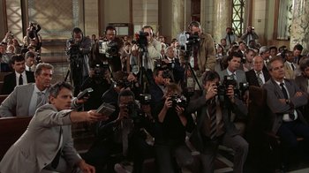 Movie still from “The Naked Gun: From the Files of Police Squad!” (1988), directed by David Zucker – A group of people taking pictures with cameras; Wide shot, Low angle