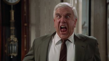 Movie still from “The Naked Gun: From the Files of Police Squad!” (1988), directed by David Zucker – An older man in a suit and tie with his mouth wide open; Close Up shot, Low angle
